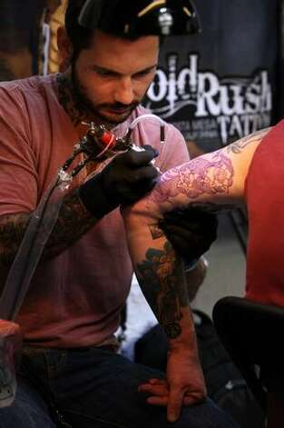A man has his upper arm tattooed on the opening day of the fifth London 