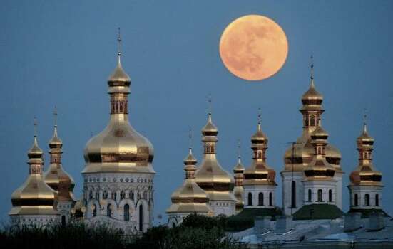 In this 2004 file photo a full moon rises in during a lunar eclipse above the golden domes of the Orthodox Monastery of Caves in Kiev, Ukraine. Celebrations marking the 1020th anniversary of this region's conversion to Christianity may turn into a fierce political battle with Ukrainian officials are determined to use the events to lobby for autonomy for the local church from Russia, while the dominant Moscow Patriarchate will fight to retain influence over this mostly Orthodox country of 46 million. Photo: Efrem Lukatsky, AP