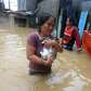 A woman carries her pet cats as she wades through a flooded street.... photo: 1630330 slideshow 31095