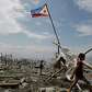 Residents walk past a tattered Philippine flag at an area where.... photo: 1646486 slideshow 31095