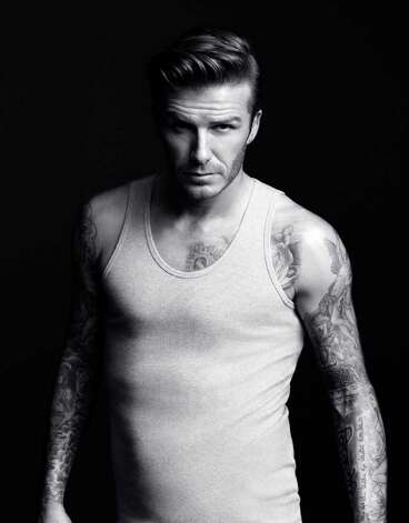 David Beckham shows off his tattoos in a gray ribbed tank top