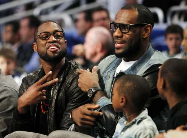 Miami Heat's Dwyane Wade, left, and Lebron James sit courtside with James' sons, LeBron Jr. and Bryce, during the NBA All-Star basketball festivities in Orlando, Fla., Saturday, Feb. 25, 2012. (AP Photo/Lynne Sladky) (AP) / SA