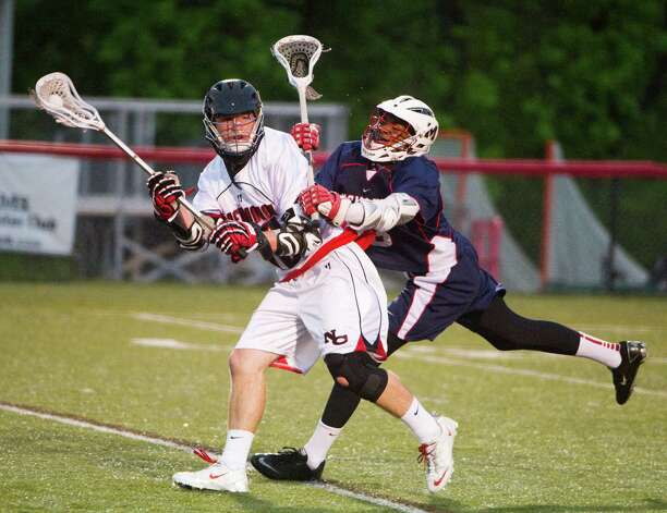 New Canaan's Peter Kraus moves the ball as McMahon's Marcel Abonyi closes in