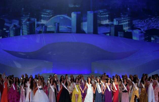 Miss World contestants hold hands and sing on stage. Photo: AP / SL