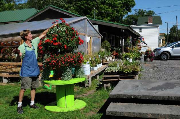 Drew Schuster tends to flowers outside of his restored Catskill Mountain Country Store, damaged by the swollen Batavia Kill in August 2011 as a result of heavy rains from Tropical Storm Irene, on Tuesday Aug. 21, 2012 in Windham, NY. Two cars sank into the formerly shattered parking area where he now stands.  (Philip Kamrass / Times Union) Photo: Philip Kamrass / AL