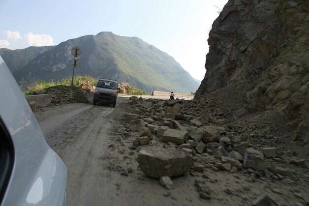 Vehicles make their way slowly along the road after a rock-fall in Yiliang, southwest China's Yunnan province on Friday after two shallow earthquakes hit the remote and mountainous border area of Yunnan and Guizhou province of southwest China.   Dozens of people were killed and 550 injured when two shallow quakes with a magnitude of both at 5.6 struck a remote and mountainous area of southwest China, toppling buildings and sparking chaos in the streets, officials said.   ( AFP/AFP/GettyImages) Photo: AFP, Ap/getty / 2012 AFP