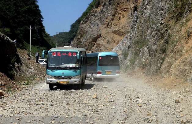 In this photo provided by China's Xinhua News Agency, buses encoutner the rockfall triggered by an earthquake in Yiliang County, southwest China's Yunnan Province, Friday. A series of earthquakes collapsed houses and triggered landslides in a remote mountainous part of southwestern China on Friday, killing at least 50 people with the toll expected to rise. Damage was preventing rescuers from reaching some outlying areas, and communications were disrupted. (AP Photo/Xinhua, Zhang Guangyu) Photo: Ap/getty / SL