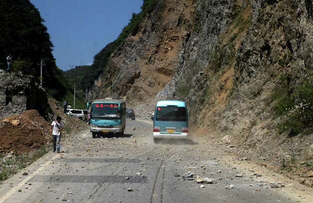 Two buses make their way across a road full of fallen rocks after a series of earthquakes, one of them measuring magnitude 5.7, hit the area near Zhaotong municipality at the border of southwest China's Yunnan and Guizhou province on Friday.  The US Geological Survey put the magnitude of the largest quake at 5.6 and said it struck at a depth of 10 kilometers.   ( STR/AFP/GettyImages) Photo: STR, Ap/getty / 2012 AFP