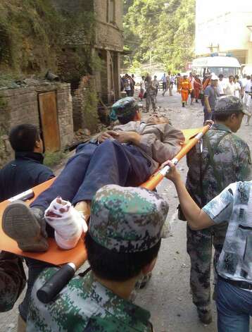 In this photo provided by Xinhua News Agency, an injured villager is carried on a stretcher by rescuers following an earthquake in Luozehe Town, Yiliang County, southwest China's Yunnan Province, Friday. A series of earthquakes collapsed houses and triggered landslides in a remote mountainous part of southwestern China on Friday, killing dozens of people with the toll expected to rise. Damage was preventing rescuers from reaching some outlying areas, and communications were disrupted. (AP Photo/Xinhua, Zhou Hongpeng) Photo: Associated Press / SL