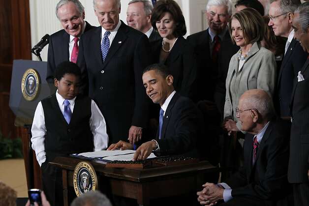 Surrounded by Democratic leaders, President Obama reaches for a pen to sign the Affordable Care Act in the East Room of the White House on March 23, 2010. Photo: Charles Dharapak, Associated Press / SF