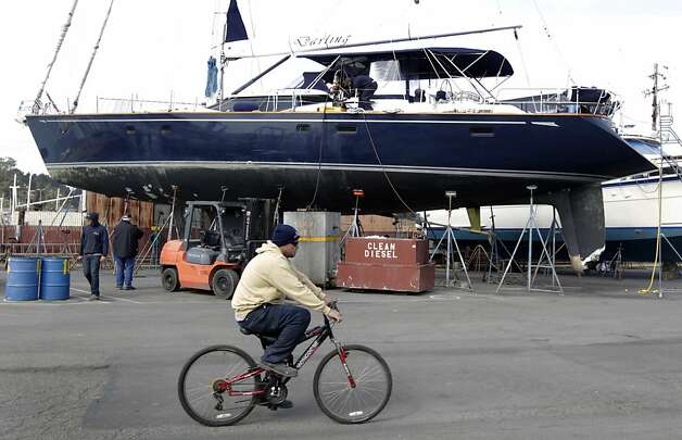A boatyard worker rides past the Darling at Bay Marine Boatworks in Richmond, Calif. on Tuesday, March 5, 2013. Three people remain in custody after they reportedly stole the 82' vessel from a marina in Sausalito and ran the boat aground in Pacifica early Monday morning. Photo: Paul Chinn, The Chronicle