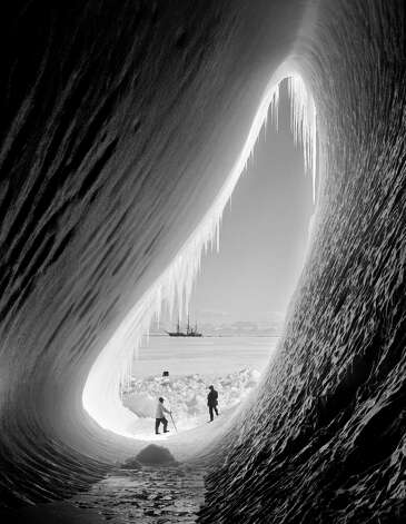 Geologist Thomas Griffith Taylor (1880 - 1963) and meteorologist Charles Wright (1887 - 1975) in the entrance to an ice grotto during Captain Robert Falcon Scott's Terra Nova Expedition to the Antarctic, 5th January 1911. The 'Terra Nova' is in the background. Photo: Scott Polar Research Institute, , H.G. Pointing/Terra Nova / 2009 Getty Images