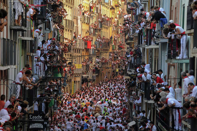 Spaniards standing on balconies watch participants as they run in front of Alcurrucen's bulls during the first bull run of the San Fermin Festival, on July 7, 2013, in Pamplona, northern Spain. The annual Fiesta de San Fermin, made famous by the 1926 novel of US 
writer Ernest Hemmingway 'The Sun Also Rises', involves the running of 
the bulls through the historic heart of Pamplona, this year for nine 
days from July 6-14. Photo: PEDRO ARMESTRE, AFP/Getty Images / 2013 AFP