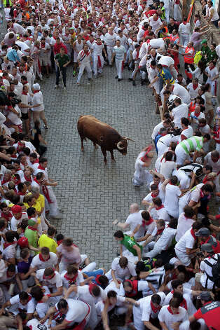 An Alcurrucen's ranch fighting bull stands alone surrounded by a crowd of runners on the way to entering the bullring during the second day of the San Fermin Running Of The Bulls festival Of The Bulls on July 7, 2013 in Pamplona, Spain. The annual Fiesta de San Fermin, made famous by the 1926 novel of US writer Ernest Hemmingway 'The Sun Also Rises', involves the running of the bulls through the historic heart of Pamplona, this year for nine days from July 6-14. Photo: Pablo Blazquez Dominguez, Getty Images / 2013 Getty Images