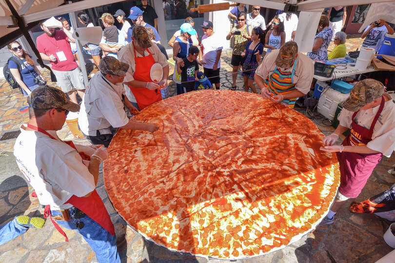 The staff of Dirt Road Cookers adds 8 lbs of pepperoni to a Guinness World Record attempt of 