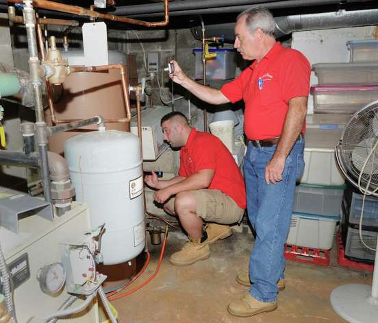 G. Neil Scott, right, and his son, Neil Scott, inspect the water heater in the basement at a McArthur Lane home in Stamford, Tuesday, August 13, 2013. G. Neil Scott is the owner of Scott and Scott Home Inspection Services Inc., of Stamford. Photo: Bob Luckey / Greenwich Time