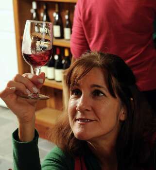 Katherine Arbiter examines a glass of wine before sampling it at the new tasting cellar at - 622x350