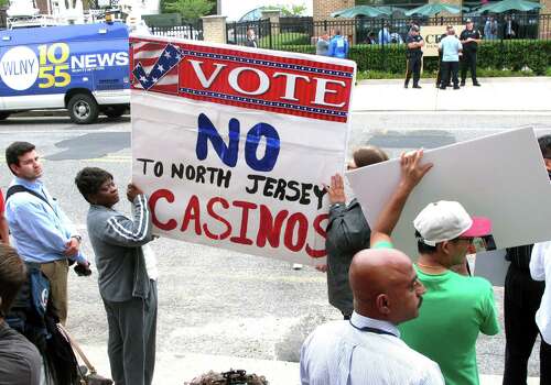 Protestors hold signs across the street from a meeting New Jersey Gov. Chris Christie convened on Monday on the future of Atlantic City, hours after Christie's administration said it will allow the casinos and horse tracks to offer sports betting. Photo: Associated Press / AP
