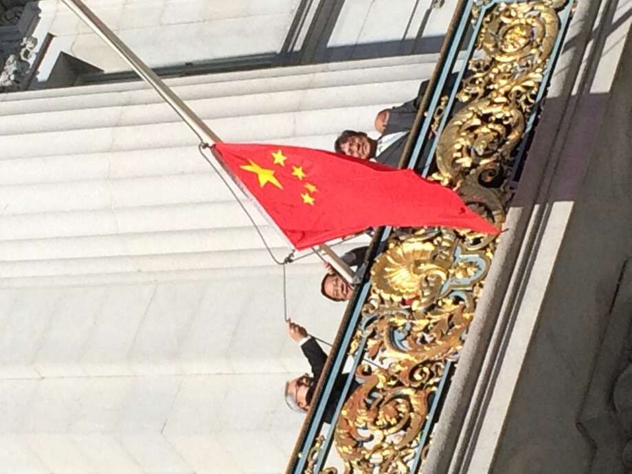Mayor Ed Lee raises the Chinese flag from his balcony at San Francisco City Hall on Oct. 1, 2014, China's National Day, as a delegation from the Chinese Consulate looks on.  The ceremony came as thousands protested in Hong Kong over China's efforts to curtail democracy there.  (John Cote / The Chronicle)