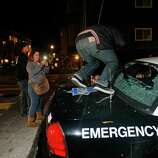 A man kicks in the back window of a police car during a riot near 22nd and Mission after the San Francisco Giants win the World Series against the Kansas City Royals Wednesday, October 29, 2014.
