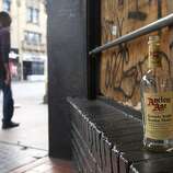An empty whisky bottle remains at a graffiti-covered storefront on Mission Street in San Francisco, Calif. on Thursday, Oct. 30, 2014. The celebration turned ugly when crowds became unruly and vandalized several businesses and vehicles after the Giants beat the Kansas City Royals in the World Series.