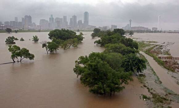 With downtown Dallas in view, water from the Trinity River floods the area below the Sylvan Avenue bridge Monday, May 25, 2015, in Dallas. Several people were reported missing in flash flooding from a line of storms that stretched from the Gulf of Mexico to the Great Lakes. (Louis DeLuca/The Dallas Morning News via AP) Photo: Louis DeLuca, Associated Press / The Dallas Morning News