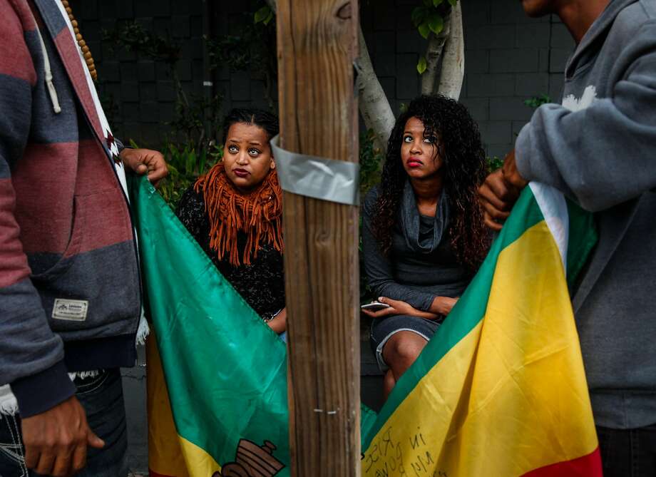 Mourners watch as an Ethiopian flag is hung on a telephone poll in Oakland at a vigil for Yonas Alehegne, a refugee who suffered mental illness and spent time at San Quentin before being fatally shot by police. Photo: Sarah Rice, Special To The Chronicle