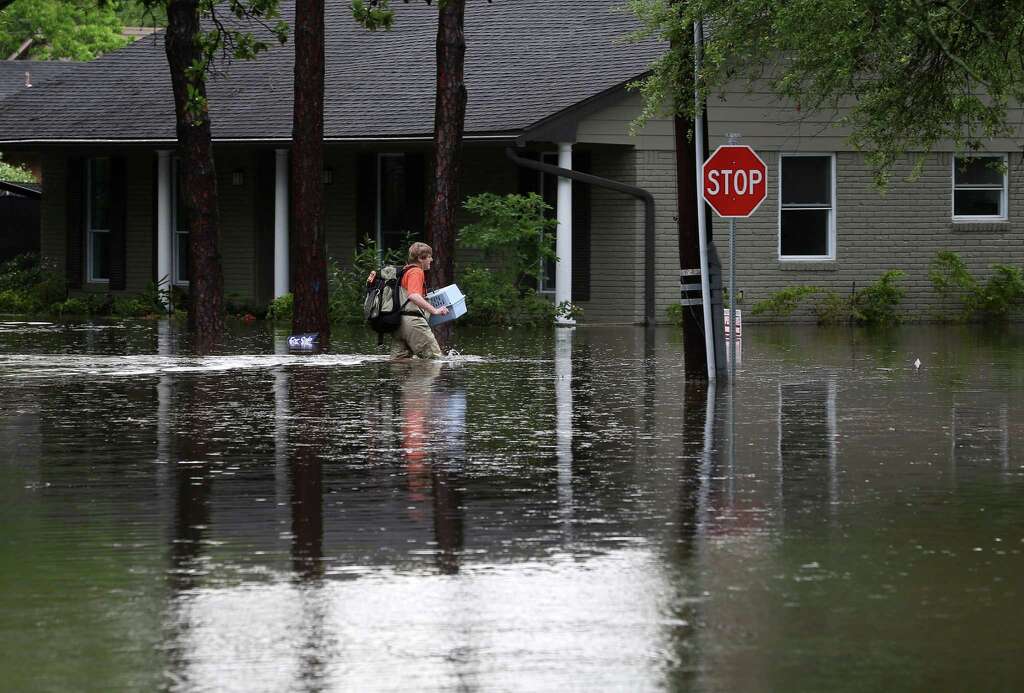 A man carries a pet carrier and other belongings through flood water, along Runnymeade Drive, in the Meyerland area, Monday, April 18, 2016, in Houston. Photo: Jon Shapley, Jon Shapley/Houston Chronicle / © 2015  Houston Chronicle