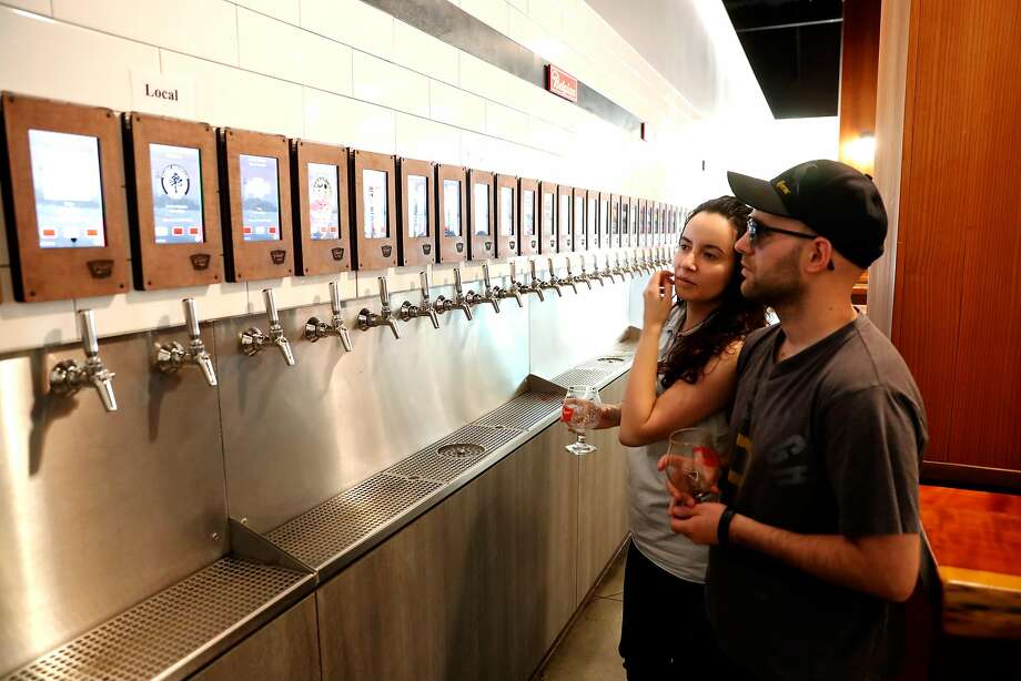 Jasmine and Mitchell Conley choose from 70 beers on tap at Pour Taproom in Santa Cruz, where customers can serve themselves with the swipe of a bracelet. Photo: Michael Macor, The Chronicle
