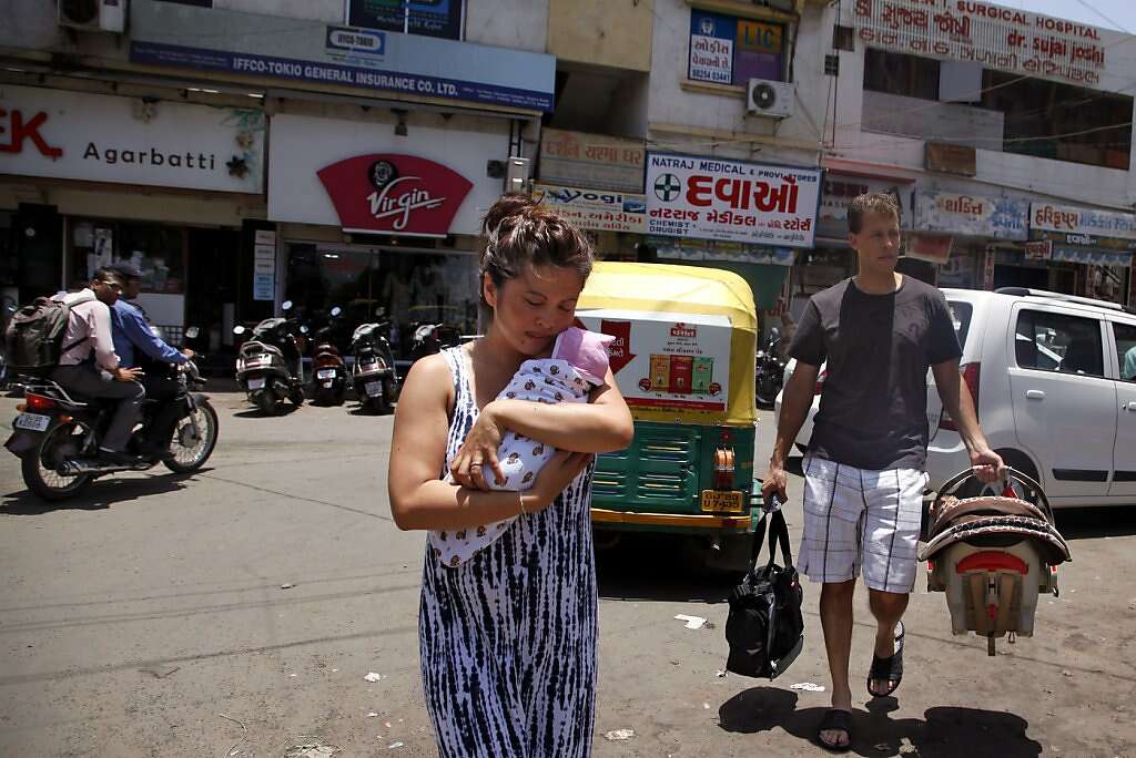 Jennifer Benito-Kowalski carries baby Kyle while husband Steve Kowalski follows with a car seat and diaper bag after Kyle was released from the Apara Nursing Home in Anand, India, Friday, May 24, 2013. Their hotel car never arrived, so the Kowalskis walked to the Akanksha Infertility Clinic to phone the hotel again. Photo: Nicole Fruge, The Chronicle