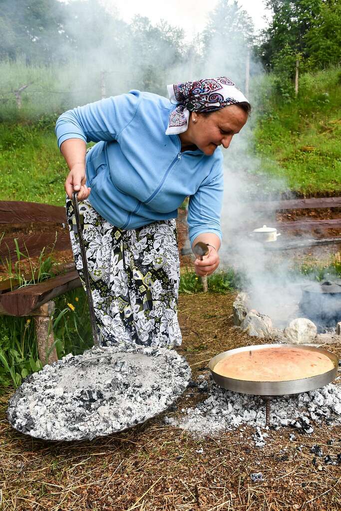 Halida Kurtishi bakes traditional Bosnian bread over coals in an outdoor pit for lunch. Photo: Margo Pfeiff, Special To The Chronicle