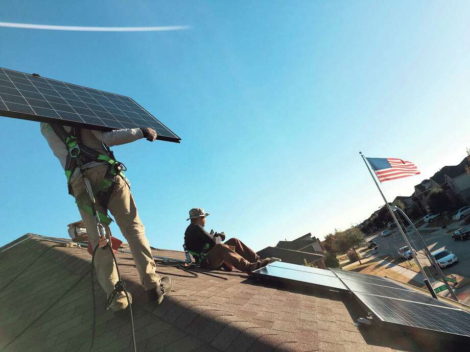Workers install a SolarCity rooftop solar system at a home in the Dallas area. SolarCity is about to enter the Houston market.
