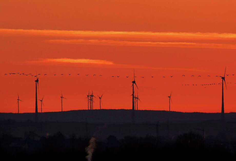 FILE - In this March 28, 2017 file photo a swarm of birds flies past wind turbines just before sunrise in the outskirts of Frankfurt, Germany. A senior EU official says Wednesday, May 31, 2017, the EU and China will reaffirm their commitment to the Paris climate change accord this week, regardless of whether President Donald Trump pulls out of the pact. The official told reporters that the EU and China will also Âspell outÂ how they plan to meet their commitments to the accord at talks in Brussels on Friday. (AP Photo/Michael Probst,file) Photo: Michael Probst, STF / Copyright 2017 The Associated Press. All rights reserved.